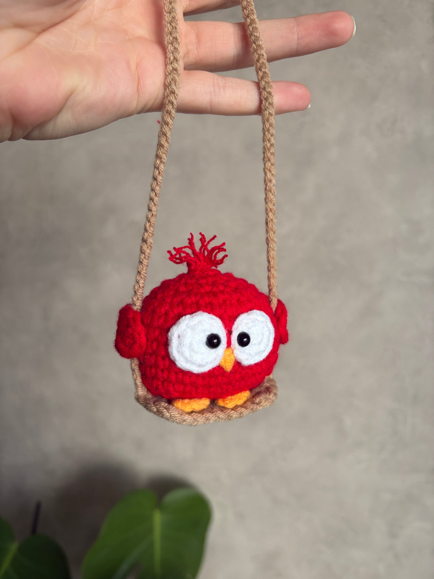 Toki l’oiseau rouge sur sa balançoire