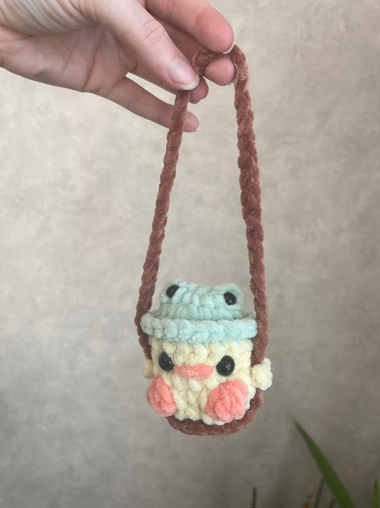 Bébé canard avec chapeau grenouille sur sa balançoire