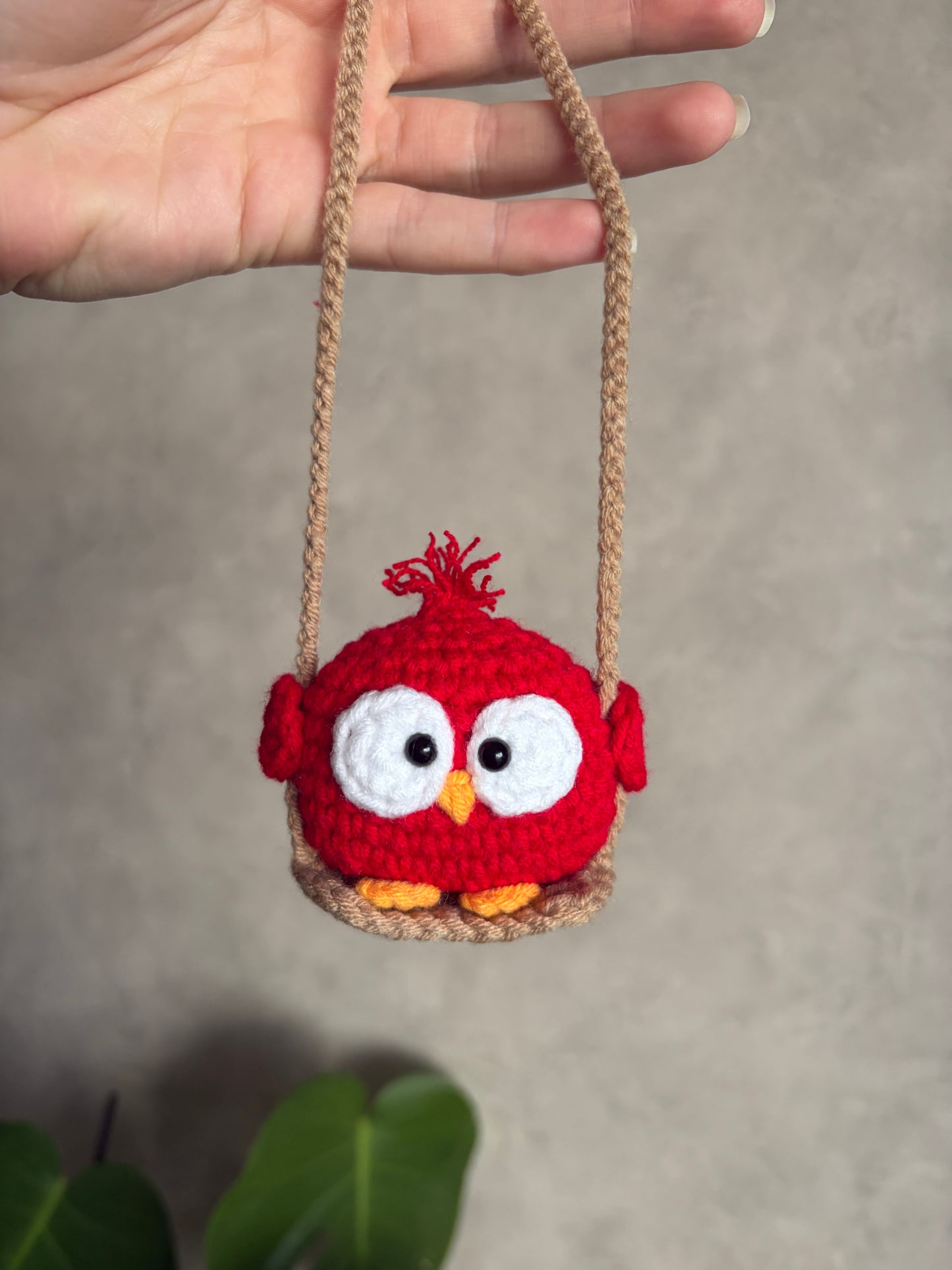 Toki l’oiseau rouge sur sa balançoire